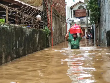 Warga berjalan menyusuri banjir yang merendam permukiman di kawasan Kebalen, Jakarta, Sabtu (20/2/2021). Curah hujan yang tinggi menyebabkan banjir setinggi orang dewasa di kawasan Kebalen. (Liputan6.com/Johan Tallo)