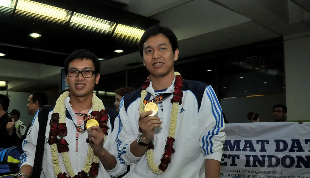 Pebulutangkis ganda putra, Mohammad Ahsan/Hendra Setiawan, memamerkan medali emas Asian Games 2014 sesaat setelah tiba di Bandara Soekarno-Hatta, Selasa (30/9/2014). (Liputan6.com/Helmi Fithriansyah)