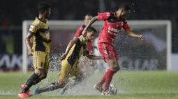 Gelandang Semen Padang, Vendry Mofu, berusaha melewati hadangan pemain Mitra Kukar, Hendra Ridwan, pada laga final Piala Jenderal Sudirman. Beberapa bagian lapangan tergenang karena hujan. (Bola.com/Vitalis Yogi Trisna)