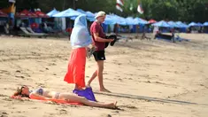 Seorang turis berjemur saat berlibur di Pantai Kuta di Denpasar, Bali (27/9). Pihak berwenang di Bali bersiap mengalihkan penerbangan jika gunung berapi di Pulau Dewata tersebut meletus. (AFP Photo/Sony Tumbelaka)