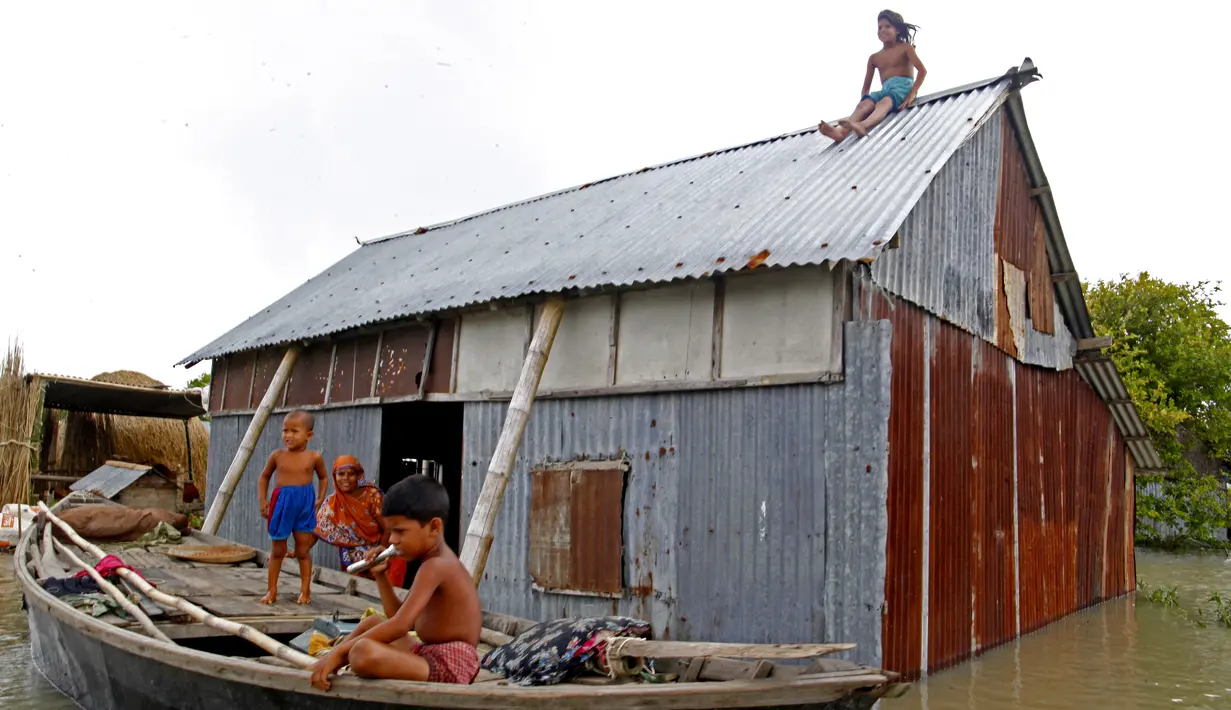Para penduduk terlihat di rumah mereka yang terendam banjir di Faridpur, Bangladesh (19/7/2020). Banjir yang dipicu tingginya curah hujan musiman dan derasnya air dari perbukitan kembali memburuk di beberapa wilayah Bangladesh, termasuk Distrik Faridpur. (Xinhua/Salim)