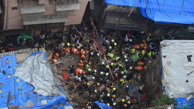 Petugas pemadam kebakaran India mencari korban setelah sebuah bangunan ambruk di Mumbai (16/7/2019). Dua orang tewas dan sedikitnya 40 terperangkap di bawah puing-puing setelah bangunan ambruk ketika hujan lebat. (AFP Photo/Punit Paranjpe)