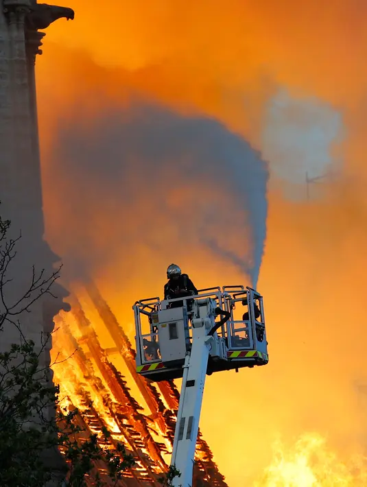 Petugas pemadam kebakaran berusaha memadamkan api dari Gereja Katedral Notre-Dame di kota Paris, Prancis, pada Senin (15/4) waktu setempat. Akibat api yang cepat menjalar, atap gereja berbahan kayu yang berusia 850 tahun itu tidak berhasil diselamatkan. (AP Photo/Francois Mori)
