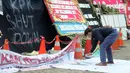 Aktivis menggunakan cat semprot menuliskan kalimat "KPK Shut Down" pada spanduk untuk dibentangkan di depan Gedung Merah Putih, Jakarta, Jumat (13/9/2019). Aksi ini bertepatan dengan terpilihnya Firli Bahuri sebagai Ketua KPK periode 2019-2023 oleh Komisi III DPR RI. (merdeka.com/Dwi Narwoko)