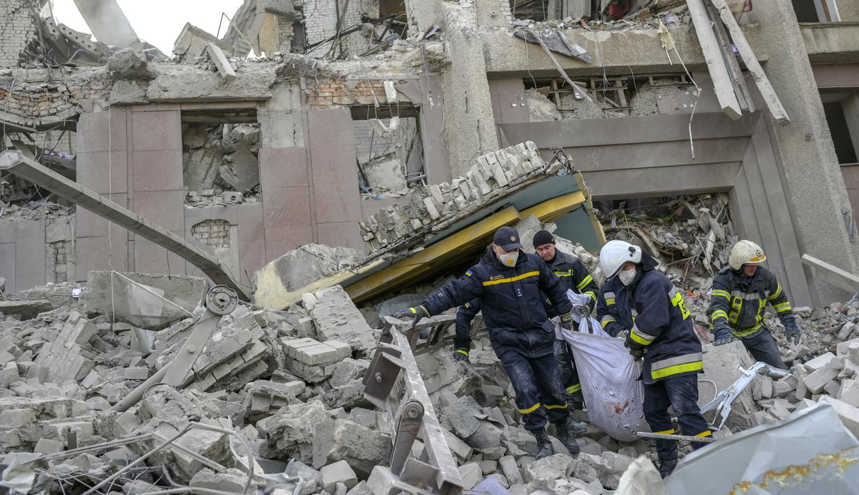 Petugas pemadam kebakaran membawa mayat dari puing-puing gedung pemerintah yang terkena roket Rusia di Mykolaiv (29/3/2022). Serangan Rusia menghancurkan gedung pemerintah daerah di kota Mykolaiv, Ukraina selatan, pelabuhan utama yang diserang selama berminggu-minggu. (AFP/Bulent Kilic)