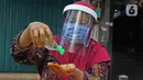 Tidar (46), memakai hand zanitizer di Pasar Baru, Jakarta, Kamis (11/06/2020). Penjual jamu tradisional keliling ini tampak mematuhi protokol kesehatan pencegahan COVID-19 dengan mengenakan masker, face shield, dan sarung tangan dalam melayani pelanggan setianya. (Liputan6.com/Herman Zakharia)