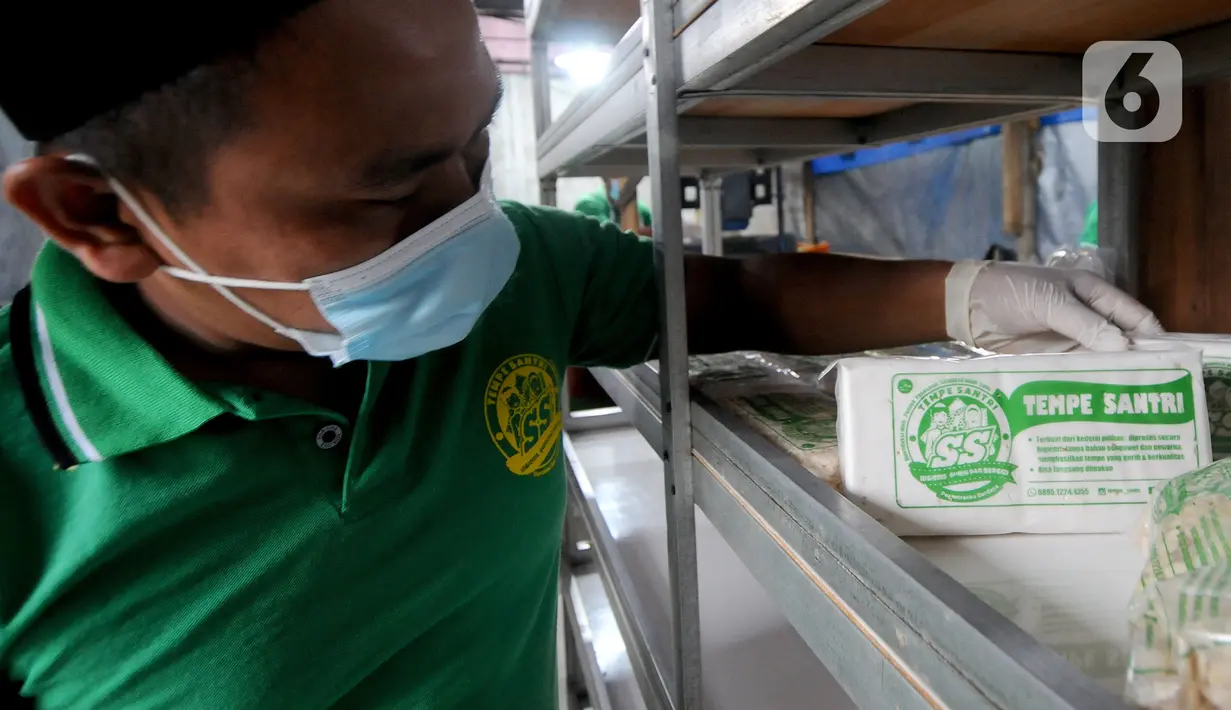 Soerang santri memperlihatkan tempe yang telah selesai dibuat di Pondok Pesantren Sirajussa'adah, Depok, Jawa Barat, Selasa (23/3/3021). Pembuatan tempe dengan merek Tempe Santri ini mampu diproduksi lebih dari dua kwintal per hari. (merdeka.com/Arie Basuki)