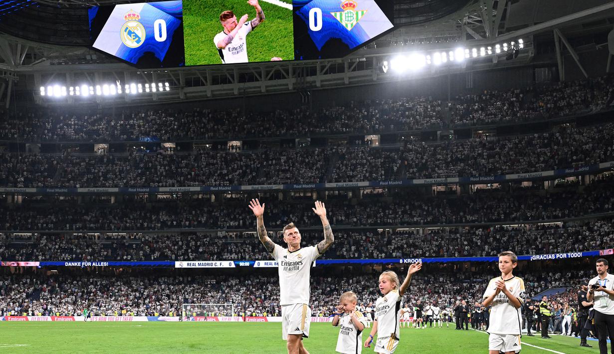 Pemain Real Madrid, Toni Kroos bersama anak-anaknya melambaikan tangan kepada para fans saat upacara perpisahan setelah laga Liga Spanyol 2023/2024 melawan Real Betis di Santiago Bernabeu, Madrid, Spanyol, Minggu (26/05/2024) dini hari WIB. Kroos memutuskan untuk pensiun dari sepak bola setelah Euro 2024 nanti. (AFP/Javier Soriano)