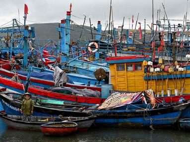 Seorang wanita memandang dari perahu kecil saat orang-orang mempersiapkan kapal penangkap ikan untuk menghadapi dampak Topan Kalmaegi di Pelabuhan Ikan Quy Nhon, Provinsi Gia Lai, Vietnam Tengah, pada 6 November 2025. (Nhac NGUYEN/AFP)