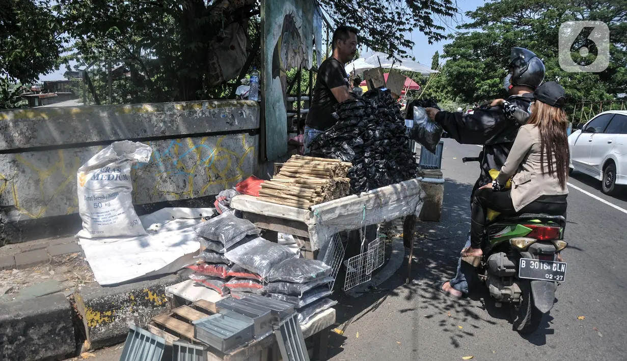 Pedagang arang melayani pembeli di kawasan Manggarai, Jakarta Selatan, Minggu (10/7/2022). Perayaan Idul Adha membawa berkah tersendiri bagi para pedagang arang musiman di kawasan Manggarai karena banya warga membeli untuk tradisi membakar sate. (merdeka.com/Iqbal S. Nugroho)