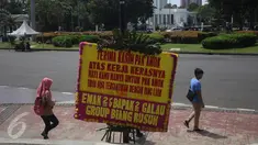 Warga berjalan di dekat karangan bunga untuk Ahok-Djarot di Taman Pandang Istana, Jakarta, Sabtu (29/4). Kiriman ribuan karangan bunga yang sebelumnya terpajang di Balai Kota Jakarta kini sudah mejalar ke depan Istana Merdeka. (Liputan6.com/Angga Yuniar)