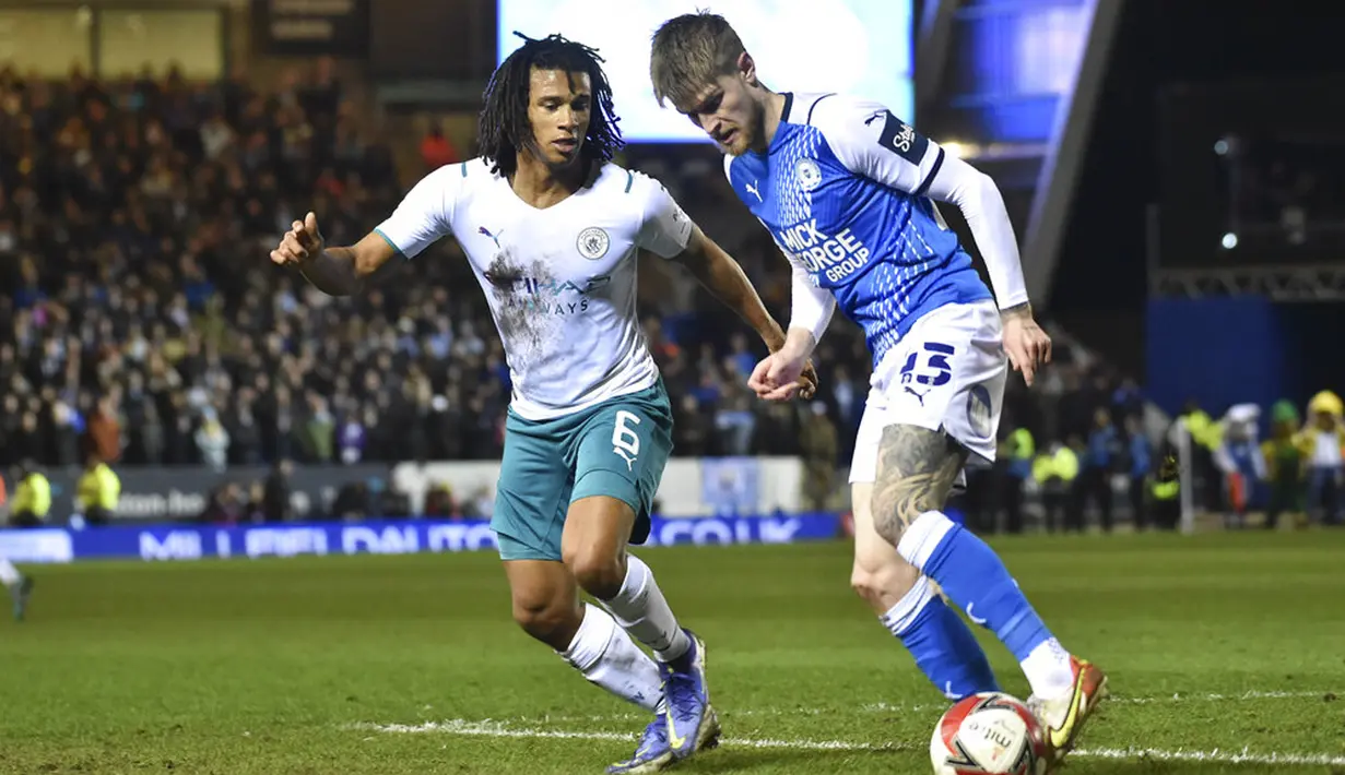 Pemain Manchester City Nathan Ake (kiri) berebut bola dengan pemain Peterborough United Hayden Coulson pada pertandingan sepak bola putaran kelima Piala FA di Stadion Weston Homes, Peterborough, Inggris, 1 Maret 2022. Manchester City menang 2-0. (AP Photo/Rui Vieira)