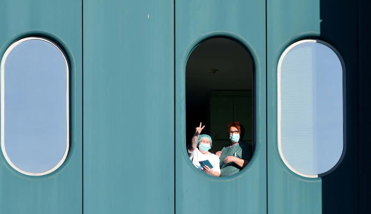 Petugas medis menunjukkan isyarat kemenangan dari jendela Rumah Sakit Dubrava, Kroasia, 15 Maret 2020. Pandemi virus corona COVID-19 membuat Kroasia menangguhkan semua layanan transportasi umum selama 30 hari ke depan. (Photo by Denis LOVROVIC/AFP)