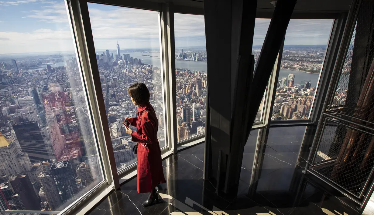 Seorang wanita menikmati pemandangan Kota Manhattan dari ruangan observatorium di lantai 102 Gedung Empire State yang baru direnovasi di New York (10/10/2019). Dibuka untuk umum pada 12 Oktober, ruang observatorium ini berjarak 1.250 kaki di atas permukaan jalan. (AFP Photo/Drew Angerer)