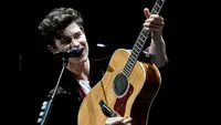 Shawn Mendes memang selalu identik dengan gitar akustik miliknya. (Liputan6.com/AFP)