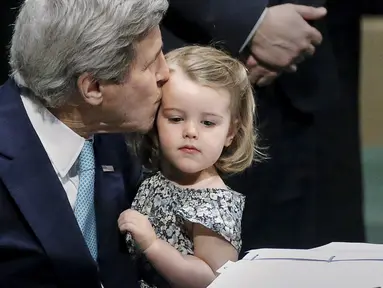Menteri Luar Negeri AS John Kerry mencium cucunya Isabelle Dobbs-Higginson saat menandatangani surat Perjanjian Paris tentang perubahan iklim di Markas Besar PBB, Manhattan, New York, AS (22/4). (REUTERS / Carlo Allegri)