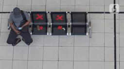 Calon penumpang melihat ponsel sambil menanti waktu keberangkatan bus Antar Kota Antar Provinsi di Terminal Bus Terpadu Pulo Gebang, Jakarta, Kamis (31/12/2020). Memasuki libur pergantian tahun sejumlah calon penumpang terus berdatangan di Terminal Bus Terpadu Pulo Gebang. (Liputan6.com/Helmi Fithri