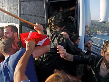 Seorang polisi melindungi tentara dari amukan warga Turki di Jembatan Bosphorus, Istanbul , Turki, (16/7).Tentara berebutan masuk kedalam bus untuk menyelamatkan diri dari pukulan warga. (REUTERS / Murad Sezer)