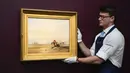 Seorang staf memegang lukisan 'Piccarie Coast with Children - Sunrise' karya Richard Parkes Bonington di Sotheby's, London, Inggris, 22 Juni 2022. Lukisan yang akan dilelang pada 29 Juni 2022 itu diperkirakan memiliki harga 2-3 juta pound. (AP Photo/Alberto Pezzali)