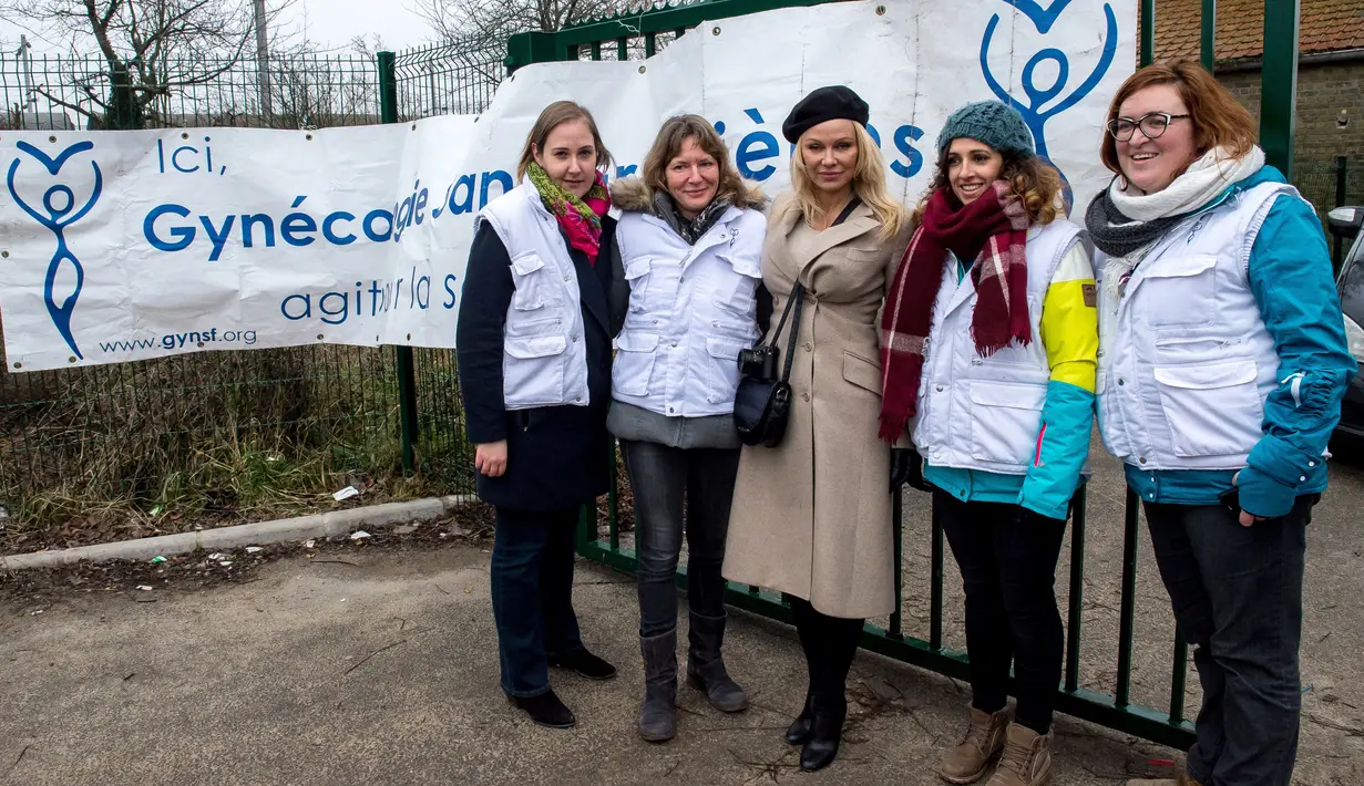 Pamela Anderson berfoto dengan sejumlah relawan di pengungsian Grande-Synthe, Prancis (25/1). Selain itu Pamela juga bermain dan menghibur anak-anak yang berada di kamp pengungsian. (AFP/Philippe Huguen)