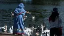 Seorang wanita memberi makan angsa saat suhu musim panas mencapai sekitar 28 derajat di Hyde Park di London, Inggris (5/7). (AFP Photo/Chris J Ratcliffe)