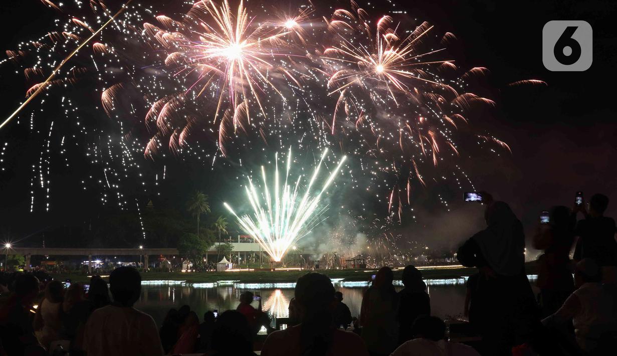 Warga menyaksikan pesta kembang api saat perayaan malam puncak Tahun Baru 2023 di Danau Archipelago, Taman Mini Indonesia Indah (TMII), Jakarta, Minggu (1/1/2023). Danau Archipelago TMII menjadi pusat pesta kembang api di malam tahun baru 2023. (Liputan6.com/Herman Zakharia)