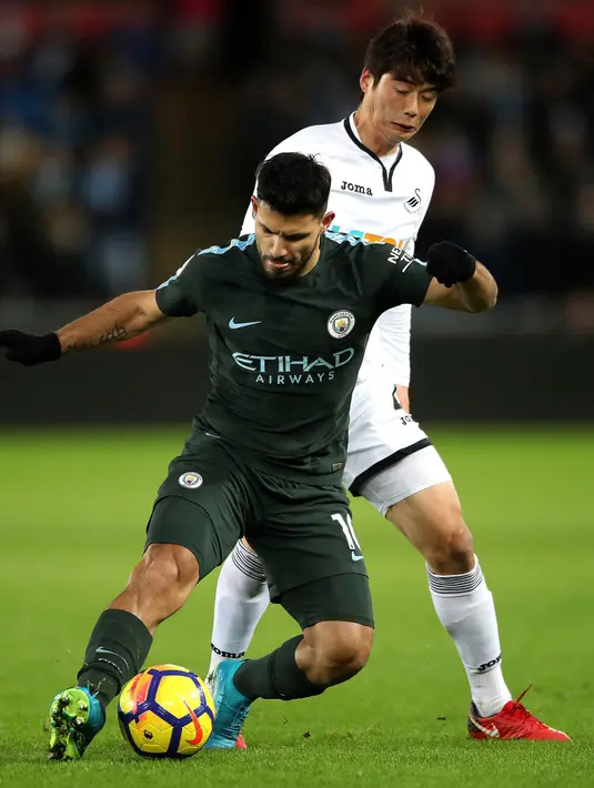 Pemain Manchester City, Sergio Aguero berebut bola dengan pemain Swansea City, Ki Sung-yueng pada lanjutan Premier League di Liberty Stadium, Rabu (13/12). Bertandang ke Swansea City, Manchester City menang telak 4-0. (Nick Potts/PA via AP)