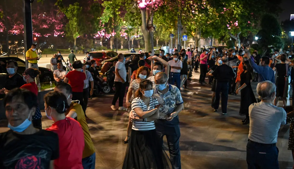 Pasangan mengenakan masker menari di sebuah taman di sebelah Sungai Yangtze, Wuhan, provinsi Hubei tengah China (12/5/2020). China melaporkan tidak ada infeksi virus corona domestik baru pada 12 Mei. (AFP/Hector Retamal)