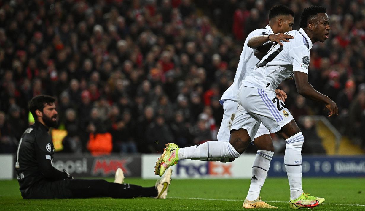 Pemain Real Madrid, Vinicius Jr melakukan selebrasi setelah mencetak gol penyeimbang 2-2 melalui blunder kiper Liverpool, Alisson Becker saat laga leg pertama Liga Champions 2022/2023 melawan Real Madrid yang berlangsung di Anfield, Rabu (22/02/2023) WIB. Liverpool kalah dengan skor 2-5 dari Real Madrid. (AFP/Paul Ellis)