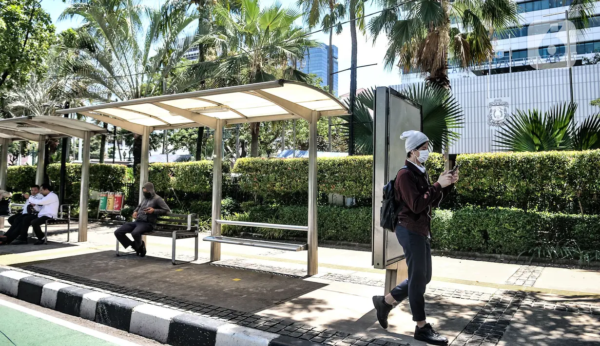 Aktivitas warga di halte depan Balai Kota, Jakarta, Selasa (1/12/2020). Sementara itu Gedung Utama Balai Kota yang terpisah dengan Kantor Gubernur Anies tetap beroperasi dengan menerapkan protokol kesehatan. (merdeka.com/Iqbal S. Nugroho)