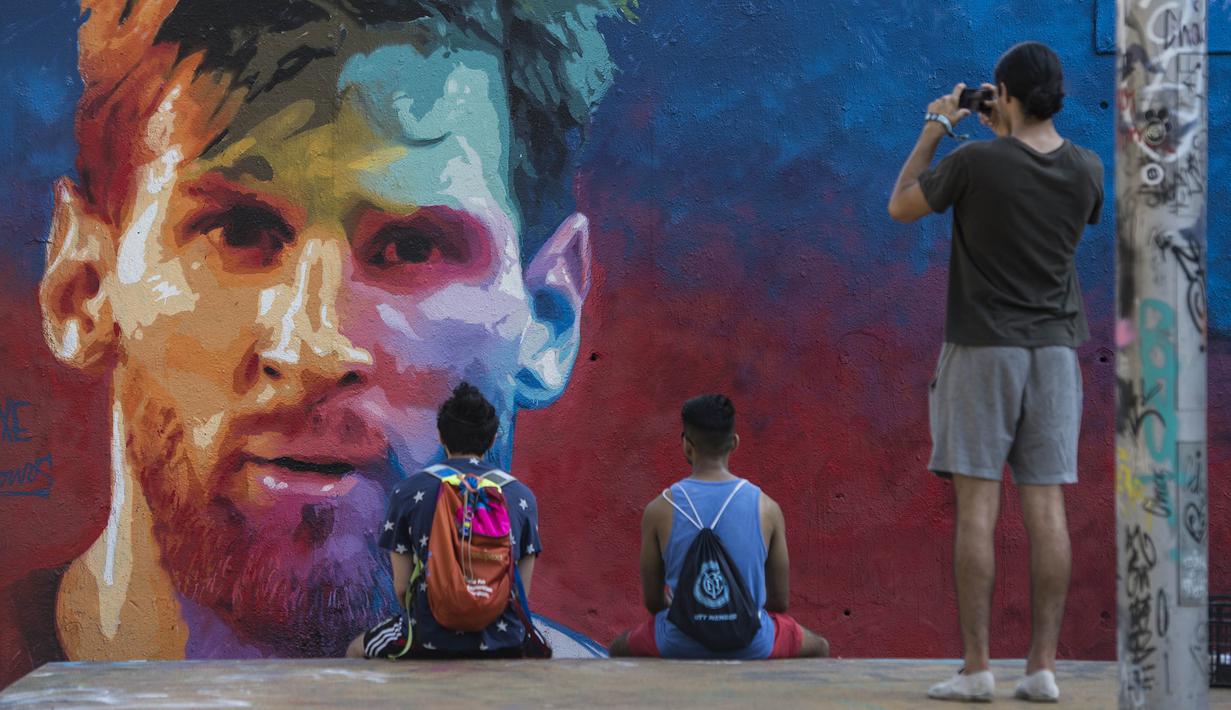 Mural bergambar wajah bintang Barcelona, Lionel Messi, menjadi daya tarik bagi warga di Barcelona, Catalonia, Sabtu (17/6/2017). (AFP/Josep Lago)