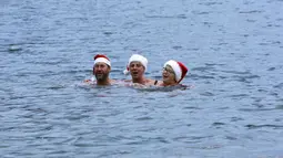 Puluhan anggota klub renang "Berliner Seehunde" merayakan Natal dengan berenang di danau Orankesee, Berlin (25/12/2014). Anggota klub "Berliner Seehunde" bernyanyi saat berenang di danau Orankesee, Berlin. (REUTERS/Fabrizio Bensch)