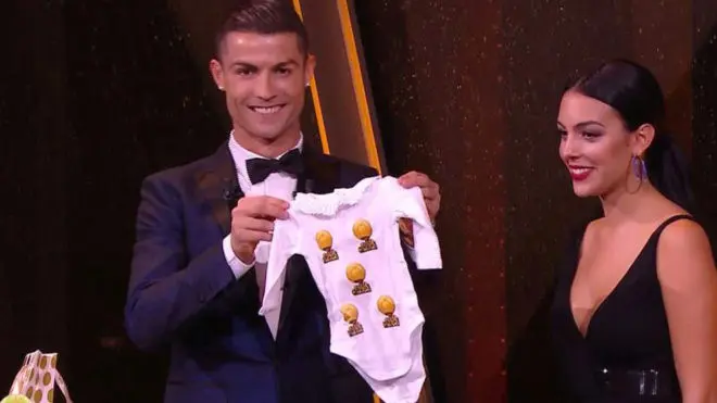 Cristiano Ronaldo dan kekasihnya, Georgina Rodriguez, memamerkan baju bayi yang diberikan pihak penyelenggara Ballon d'Or 2017. (Marca)