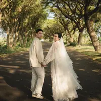 Dress lace tersebut dipadukan dengan veil bertumpuk putih yang memaksimalkan tampilannya. Sedangkan sang calon suami mengenakan kemeja lengan panjang beige dipadukan celana panjang warna senada. [@bebytsabina]