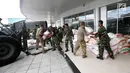Prajurit TNI dibantu tentara Amerika Serikat mendistribusikan bantuan logistik yang tiba di Bandara Mutiara Sis Al-Jufri, Palu, Sulawesi Tengah, Minggu (7/10). Bantuan asing tiba menggunakan pesawat Hercules. (Liputan6.com/Fery Pradolo)