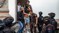 Salah satu tersangka kasus pembunuhan berencana terhadap warga negara Australia yaitu Zivan Radmanovic dan korban luka Sanar Ghanim, Darcy Francesco Jenson (tengah) dibawa kembali ke rumah tahanan setelah menjalani pemeriksaan oleh pihak kejaksaan di Badung, Bali, pada 15 Oktober 2025. (Dicky Bisinglasi/AFP)