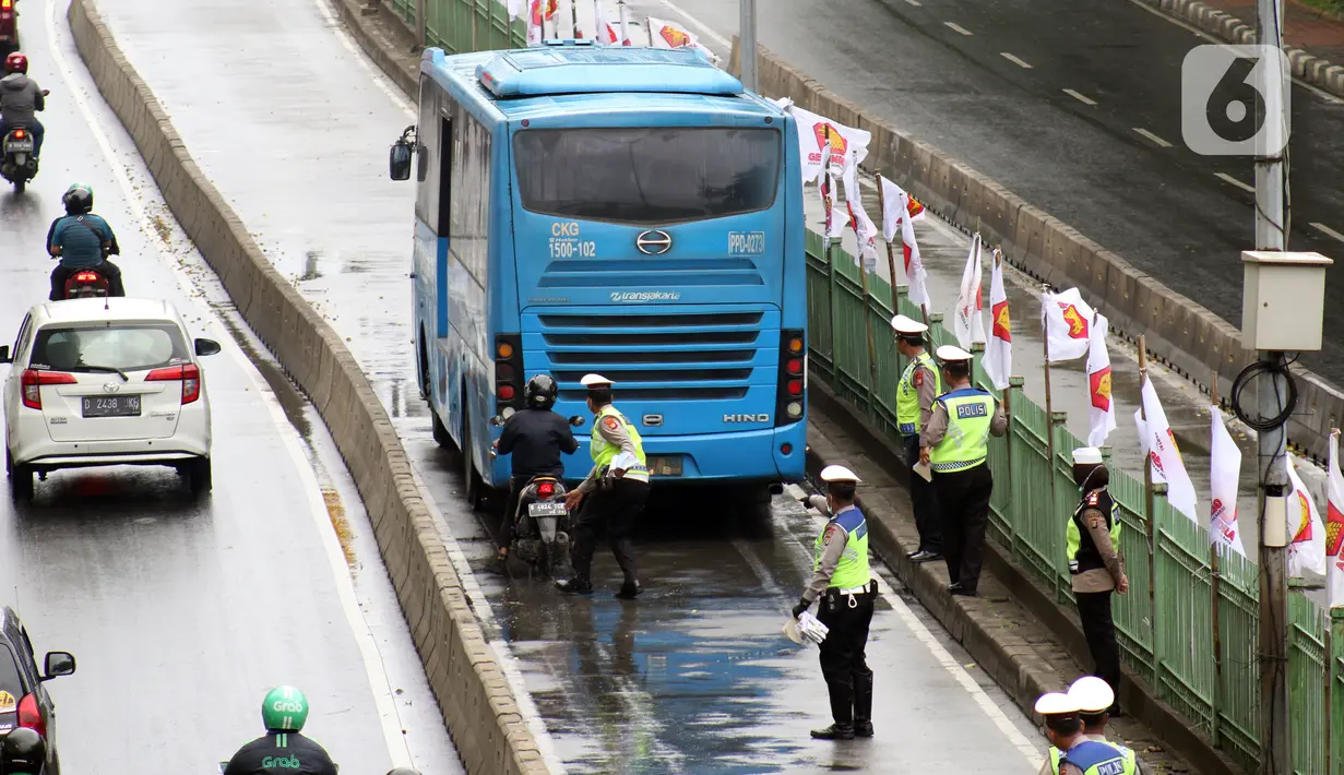 Petugas kepolisian berusaha menghentikan laju pengendara motor yang melintasi jalur bus Transjakarta di Jalan Sultan Agung, Manggarai, Jakarta, Kamis (6/2/2020). Meski melanggar, sebagian pengguna jalan secara sengaja masuk dan menggunakan jalur khusus bus tersebut. (Liputan6.com/Helmi Fithriansyah)