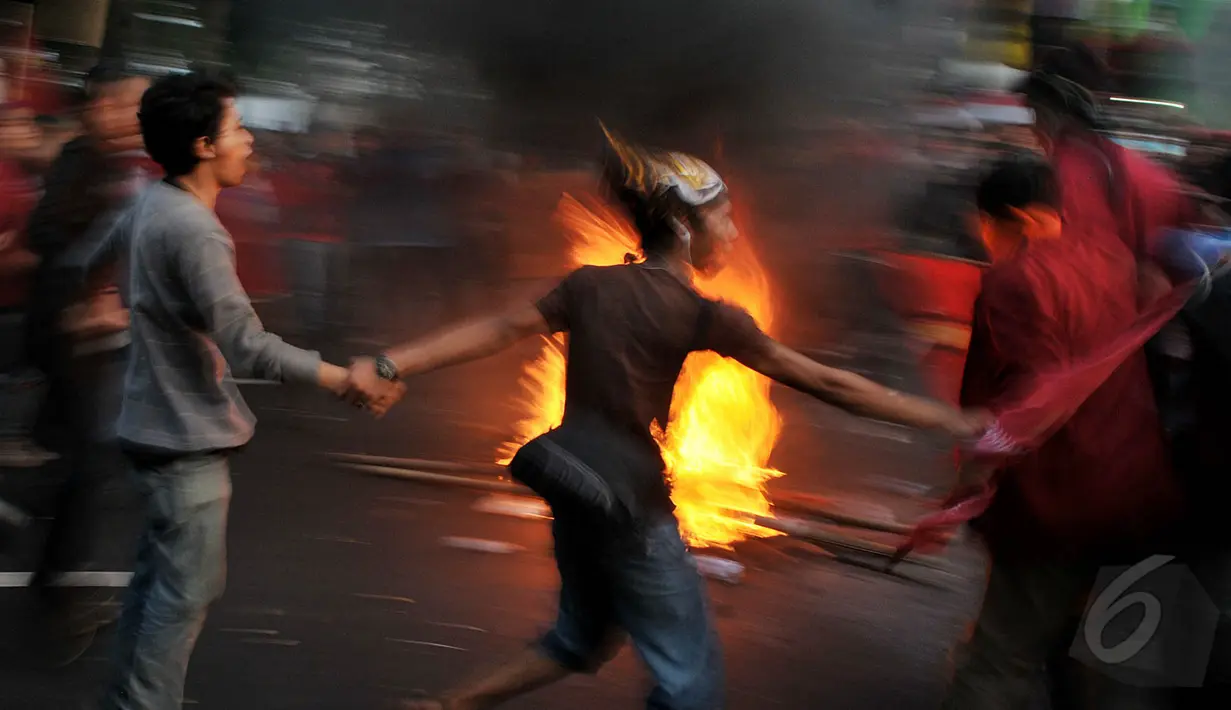 Sejumlah mahasiswa mengitari api sambil menari saat aksi di depan Istana Negara, Jakarta, Kamis (21/5/2015). Mereka menuntut Jokowi-JK untuk turun karena dinilai telah gagal memimpin. (Liputan6.Com/JohanTallo)