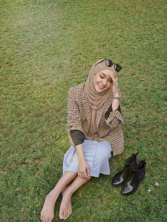 Kali ini Cita Citata tampil dengan dalaman polos hijau tua yang dipadukan dengan blazer oversized kotak-kotak, rok biru muda tanpa motif, plus jilbab polos warna turangga. Kaca mata hitam bertengger di atas kepala. Pose duduk di rerumputan sambil memejamkan mata ini diunggah pada Senin (8/8/2022) dan disukai lebih dari 15 ribu warganet. (Foto: Dok. Instagram @cita_citata)