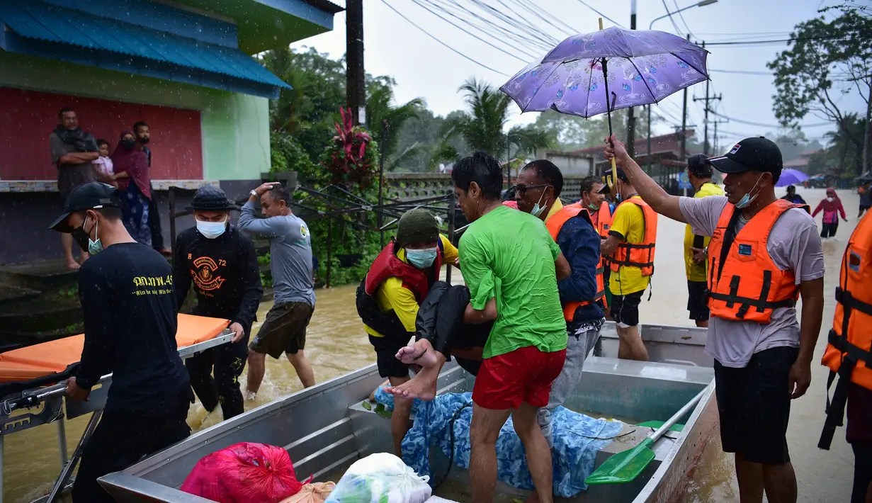 Warga diangkut melalui banjir di distrik Ran-ngea di provinsi Narathiwat, Thailand selatan (26/2/2022). Hujan yang disebabkan oleh angin timur laut di atas Teluk Thailand terus berlanjut selama tiga hari berturut-turut di provinsi perbatasan selatan ini. (AFP/Madaree Tohlala)