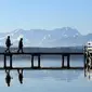 Pejalan kaki berjalan melewati panorama pegunungan alpine di danau Starnberger See, Jerman (25/2). Pegunungan ini membentang dari Austria dan Slovenia di timur, melalui Italia, Swiss, Liechtenstein, Jerman sampai ke Prancis. (AFP Photo/Christof Stache)