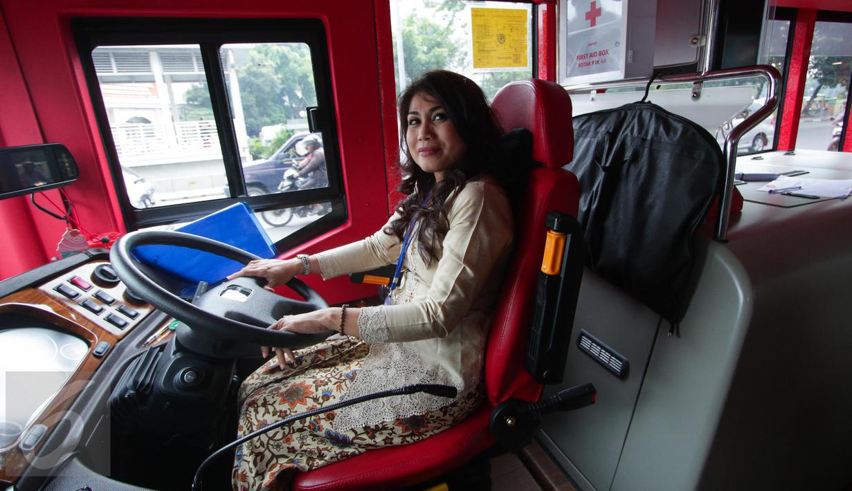 Seorang pramudi bus tingkat wisata TransJakarta mengenakan kebaya saat mengendarai bus tersebut di Jakarta, Jumat (21/4). Dalam rangka Hari Kartini, semua pramudi perempuan bus pariwisata dan Transjakarta mengenakan kebaya. (Liputan6.com/Faizal Fanani)
