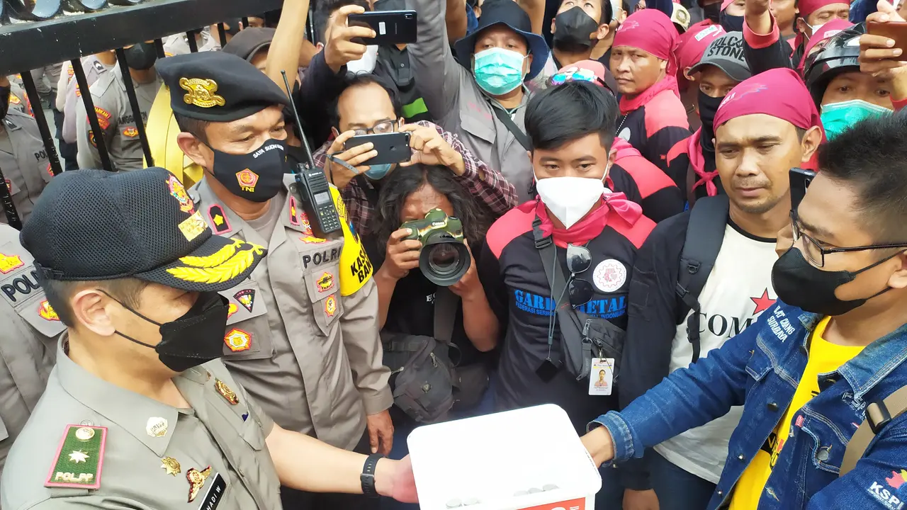 Buruh di Jatim menyerahkan uang koin ke perwakilan Pemprov Jatim. (Dian Kurniawan/Liputan6.com)