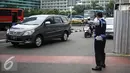 Petugas Dishub mengantur lalu lintas di kawasan Thamrin, Jakarta, Rabu (25/7). Proses pengawasan ganjil genap akan dilakukan secara manual, yakni petugas akan mengamati pelat kendaraan yang berhenti saat lampu merah. (Liputan6.com/Faizal Fanani)