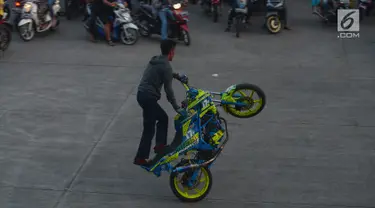 Seorang bikers melakukan aksi freestyle dengan motor di kawasan Kanal Banjir Timur, Jakarta, Selasa (29/5).Sekelompok pemuda di kawasan itu memanfaatkan waktu menunggu berbuka dengan melakukan atraksi freestyle yang mendebarkan. (Merdeka.com/Imam Buhori)