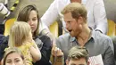 Pangeran Harry mengambilkan Emily Henson popcorn dan menyuapinya ketika acara Invictus Games 2017 di Toronto, Kanada, Rabu (27/9). Bocah itu merupakan anak atlet David Henson yang juga rekan dari Pangeran Harry. (CHRIS JACKSON/GETTY IMAGES/AFP) 