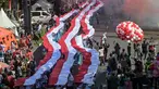 Para siswa dari berbagai sekolah membentangkan bendera Merah Putih panjang saat berbaris di jalan-jalan selama acara upacara untuk memperingati HUT ke-80 Kemerdekaan Indonesia di Surabaya, Jawa Timur pada 17 Agustus 2025. (Juni KRISWANTO/AFP)