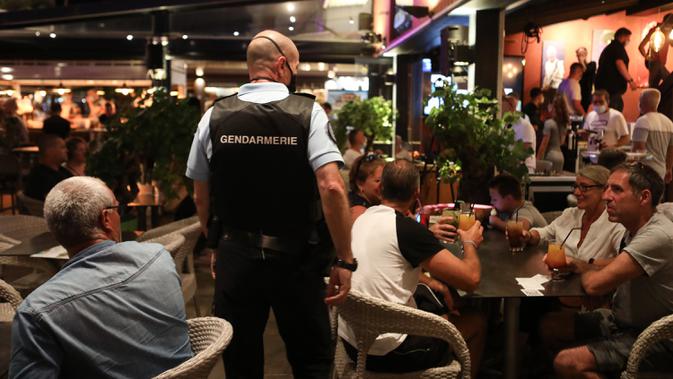 Polisi Prancis berpatroli di sebuah bar untuk mengontrol penggunaan masker di jalan-jalan Argeles-sur-Mer, Rabu (13/8/2020). Pemakaian masker di beberapa area ramai di sekitar Paris merupakan kewajiban sebagai upaya untuk membendung peningkatan tajam infeksi covid-19. (RAYMOND ROIG/AFP)