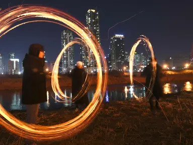 Peserta memutar kaleng arang yang terbakar menjelang perayaan "Jeongwol Daeboreum" (Bulan Purnama) di sebuah taman di Seoul, Korea Selatan (1/3). Permainan ini dipercaya dapat menyuburkan tanah dan menyingkirkannya hama. (AFP Photo/Jung Yeon-je)