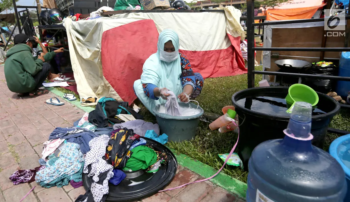 Pengungsi korban gempa dan tsunami Palu mencuci pakaian di tenda pengungsian lapangan Walikota Palu, Sulawesi Tengah, Senin (8/10). Pemerintah tengah menentukan lokasi yang tepat untuk membangun hunian sementara bagi korban. (Liputan6.com/Fery Pradolo)